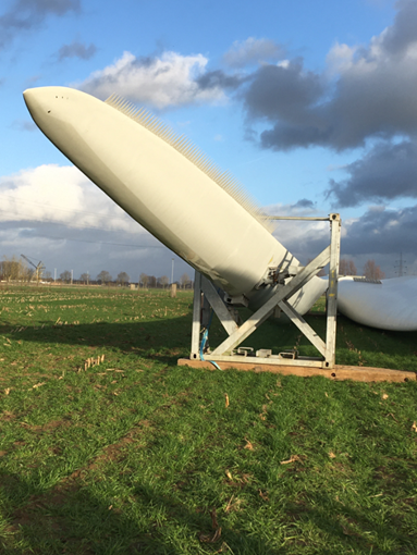 Foto: Links: Een wiek van de windturbine van de Huysmanhoeve in opbouw. De driehoekjes op de uiteinden verminderen het geluidsniveau.