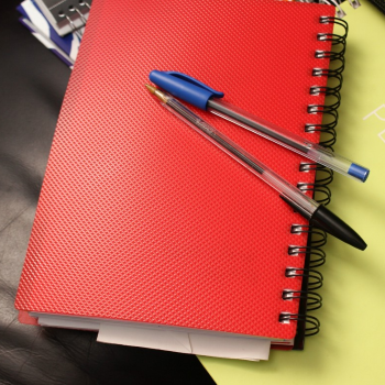 rood notitieboekje met twee balpennen