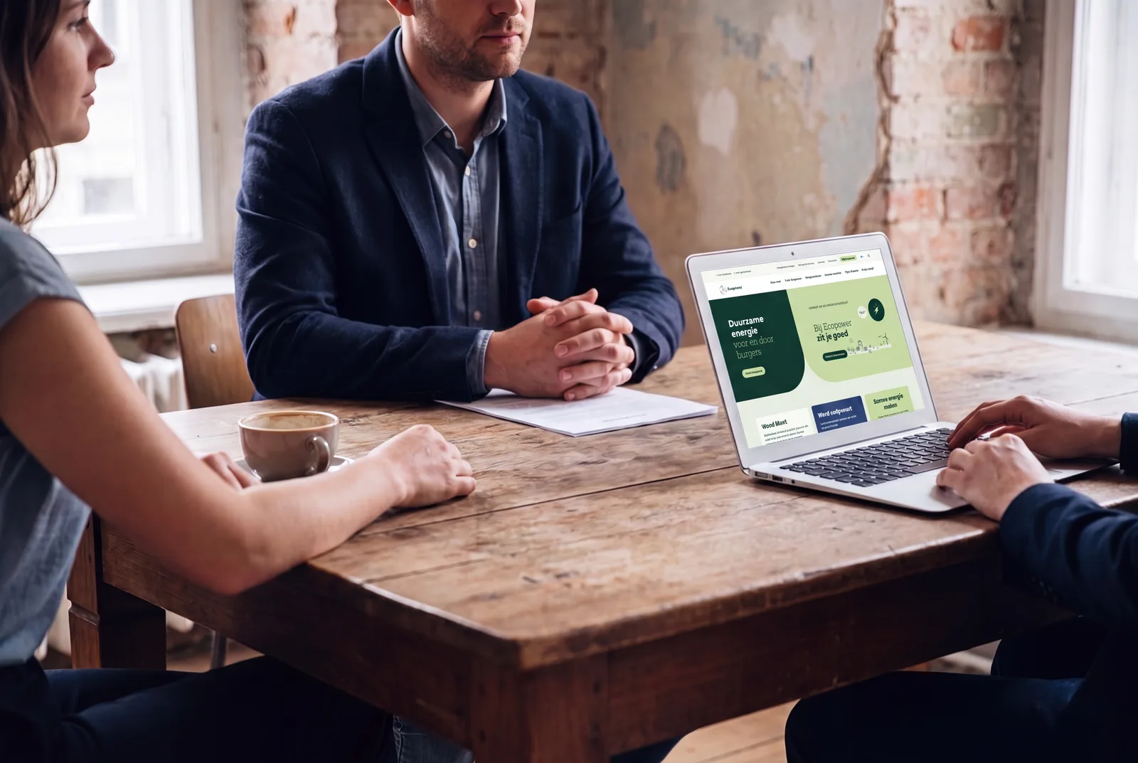 Klantgesprek aan tafel met een digitaal product op het scherm