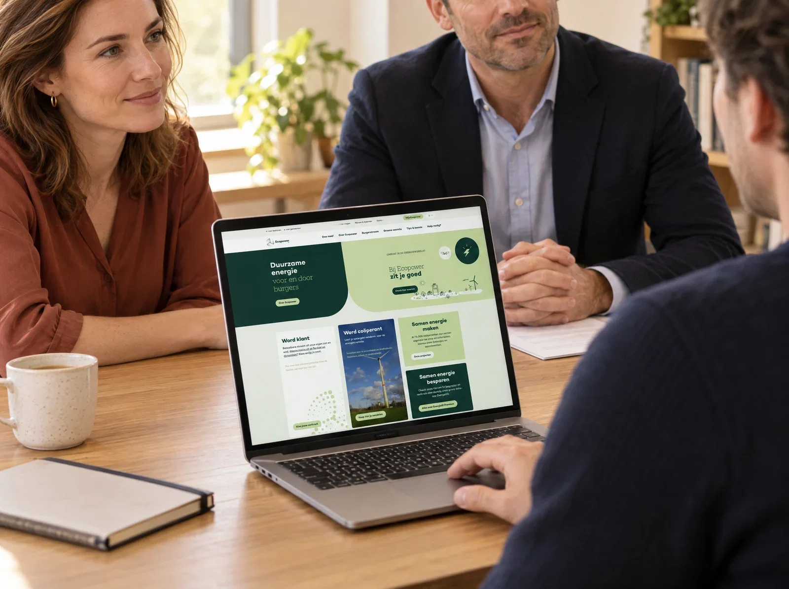 Klantgesprek aan tafel met een digitaal product op het scherm