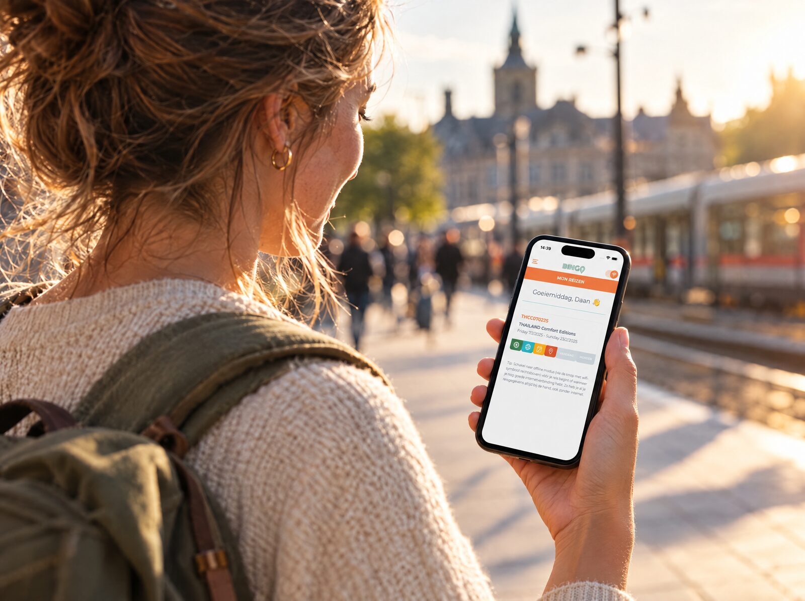 Reizigster bekijkt haar reisoverzicht in de Karavaan-app op haar smartphone op een stationsperron