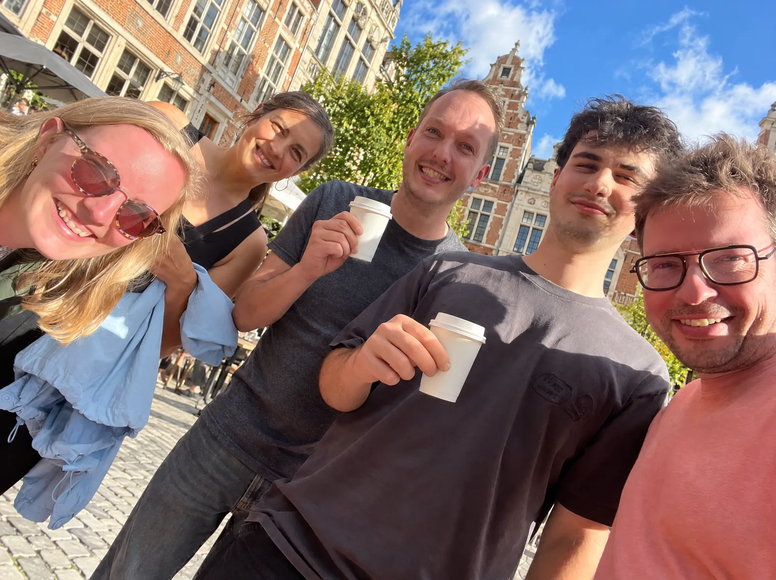Collega's met koffie in een zonnige straat in Leuven