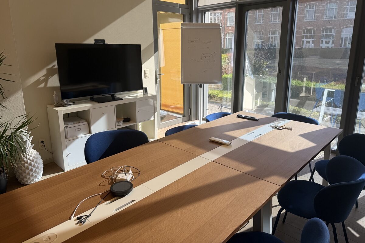 Vergaderzaal van Zenjoy met een lange tafel, een scherm en een flip-over bij het raam