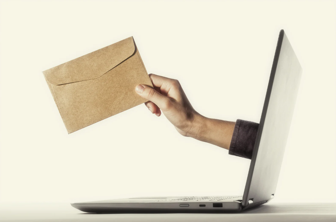 Hand reaching out off a computer screen holding an envelop.