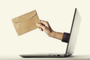Hand reaching out off a computer screen holding an envelop.