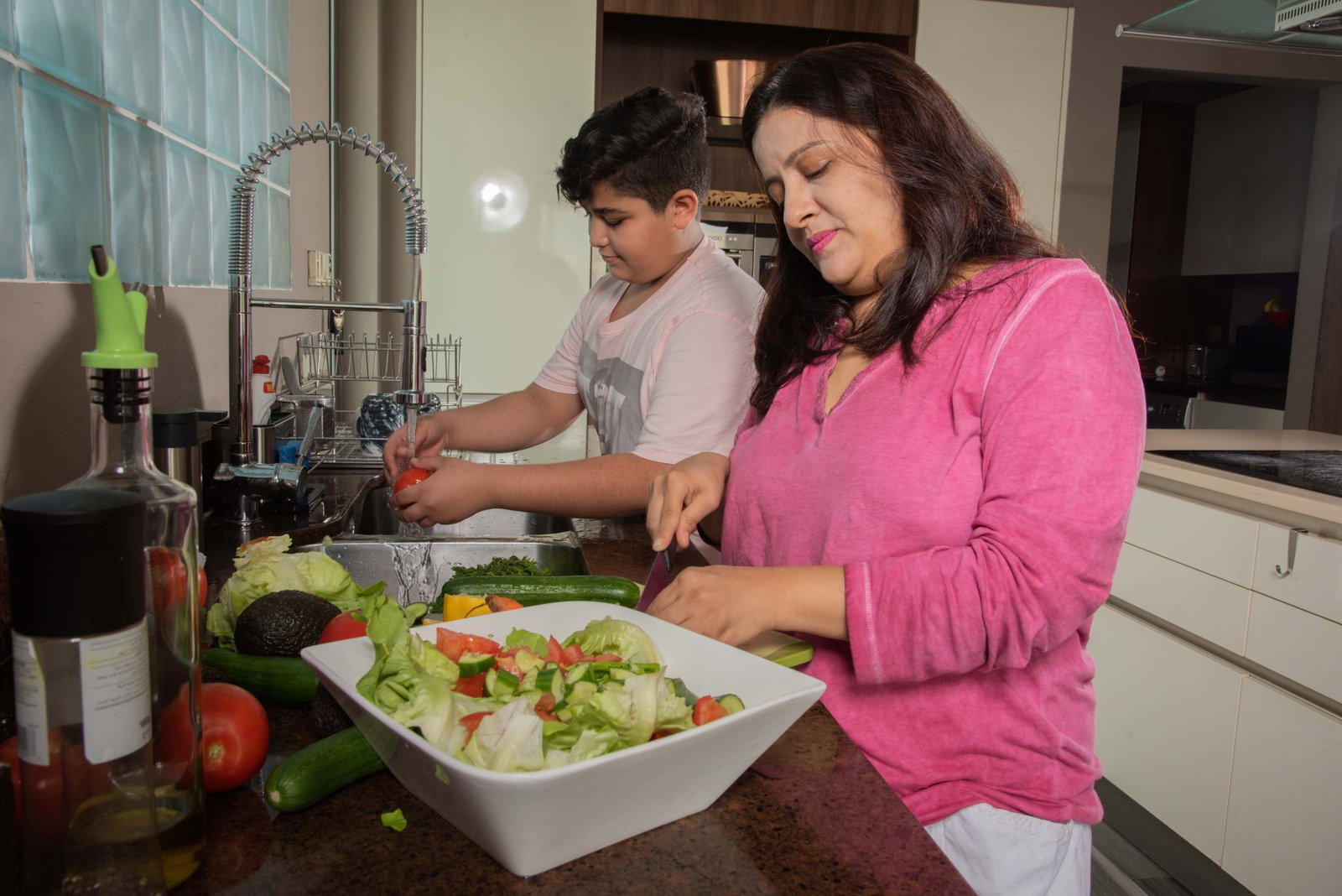Een moeder en zoon maken samen eten klaar.